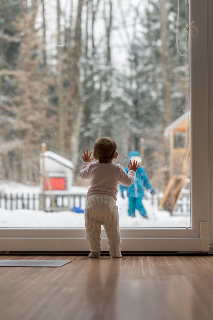 Toddler looking out of garden room window in winter